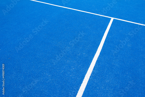 partial view of a blue paddle tennis court with artificial grass