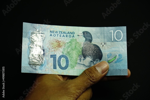 10 NZD, ten New Zealand Dollar money was held by businessman on black background photo