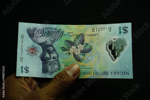 1 BND, one Brunei Darussalam Dollar money, was held by businessman, money concept isolated on black background photo