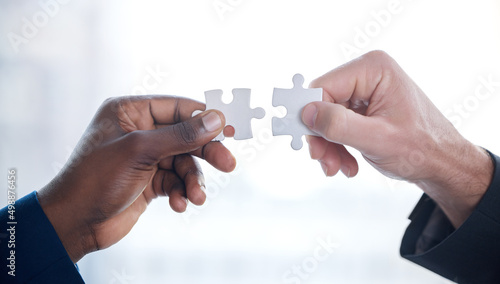 Problems are better solved together. Cropped shot of two unrecognizable businesspeople completing a puzzle together in a modern office.