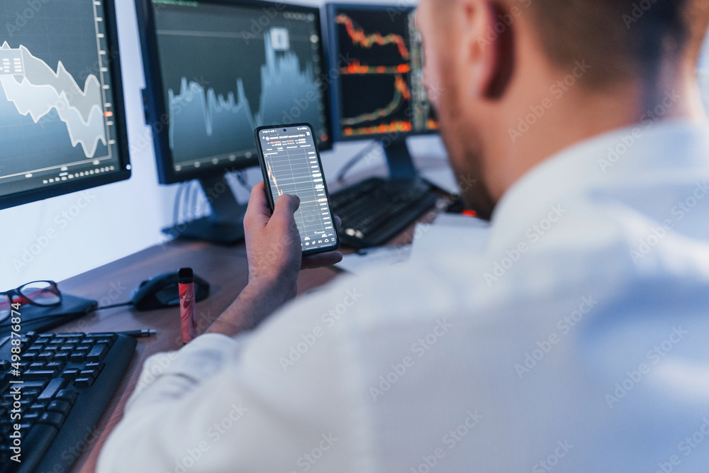 Using phone. Stock trader working in the office with exchange technology Using phone. Stock trader working in the office with exchange technology