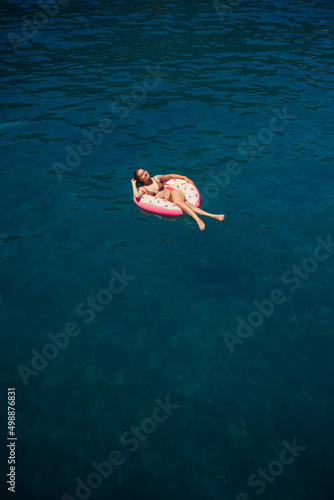Young woman in a swimsuit swims on an inflatable ring in the sea. Summer vacation concept.