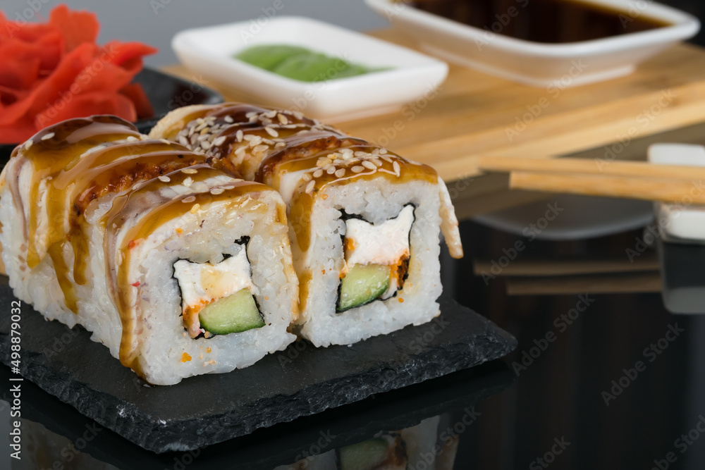 a set of rolls with eel and sauces for them on a black table a set of rolls with eel and sauces for them on a black table