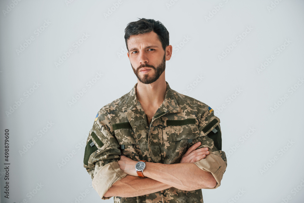 Soldier in uniform is standing indoors against white wall