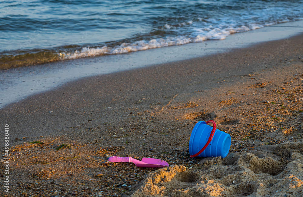 Φωτογραφία Children's toys on a sandy beach, blue sky and the sea in the background