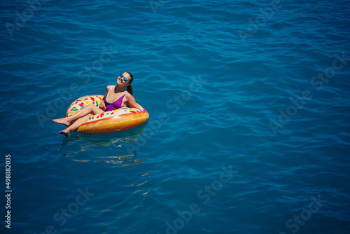 Carefree young woman enjoying a relaxing day at sea, floating on an inflatable ring. Sea vacation concept