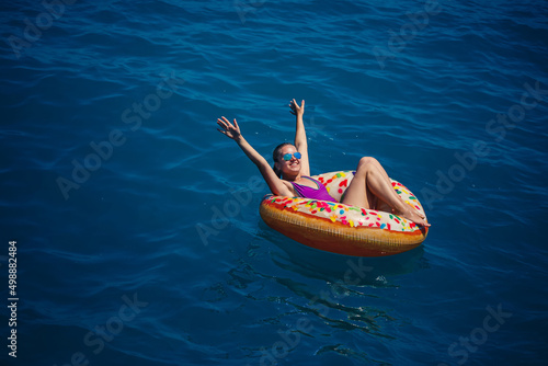 Carefree young girl woman enjoying a relaxing day at sea, floating on an inflatable ring, top view. Sea vacation concept