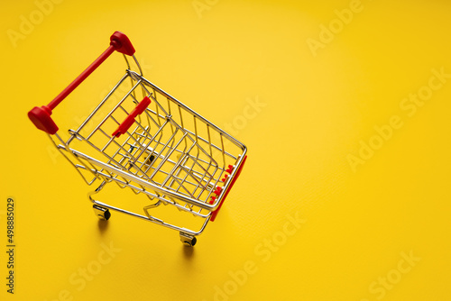 Shopping cart on yellow background with copy space. Shopping concept