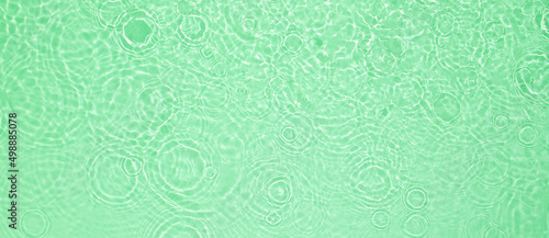 Abstract summer banner background Transparent green clear water surface texture with ripples and splashes. Water waves in sunlight, copy space, top view Cosmetics moisturizer micellar toner emulsion