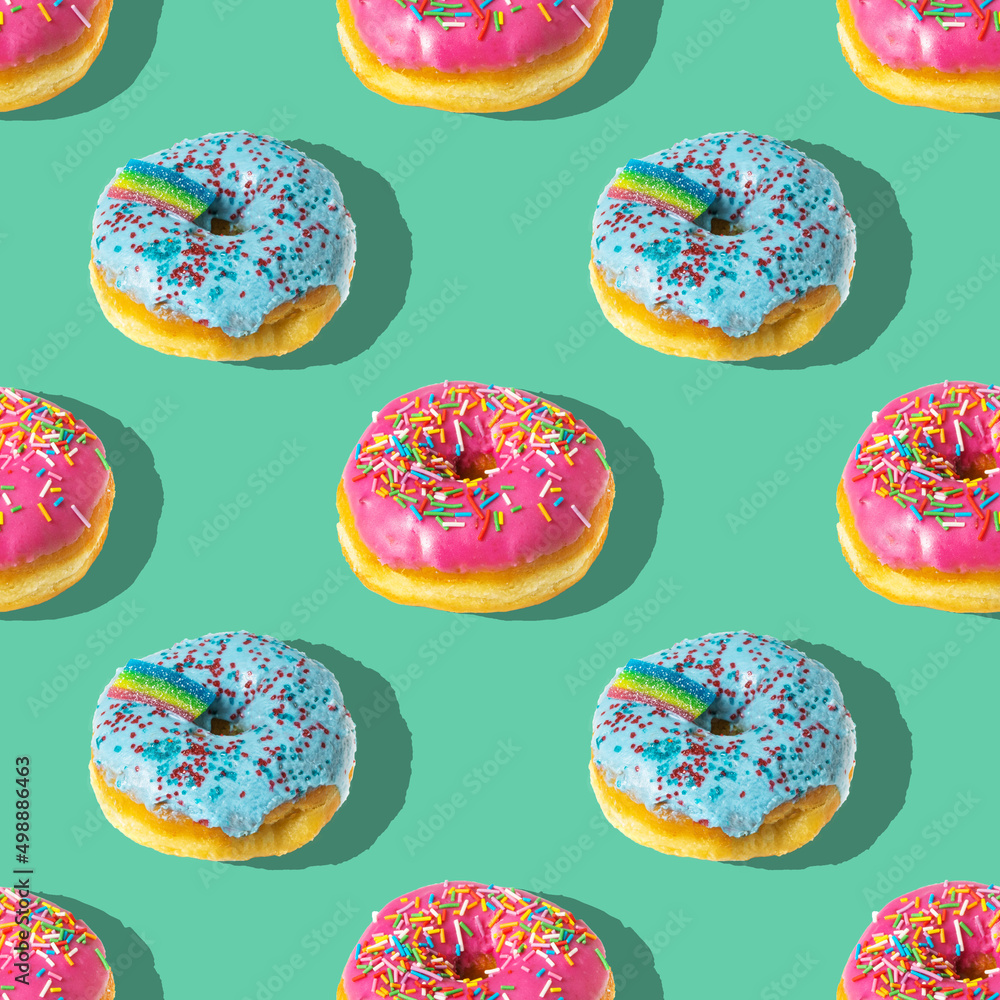 Repeating pattern of pink and blue rainbow donuts on a blue background Repeating pattern of pink and blue rainbow donuts on a blue background