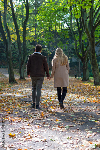 Obraz na płótnie A couple in love in a park in autumn, holding hands and walking. w salonie