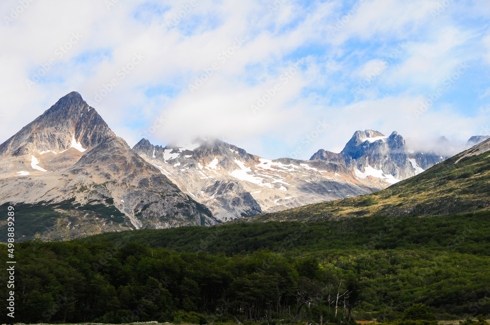 Mountain peaks covered with snow and hills with grass and vegetation Mountain peaks covered with snow and hills with grass and vegetation