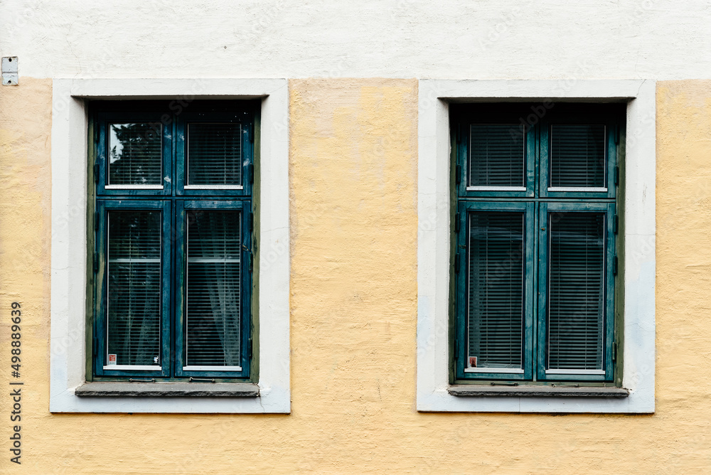 Two old wooden windows painted in green on stucco facade