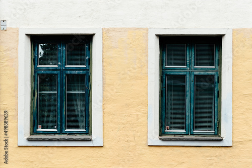 Two old wooden windows painted in green on stucco facade