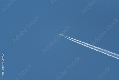 Airplane trail on a blue cloudless sky. Traveling by plane on vacation.