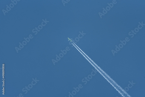 Airplane trail on a blue cloudless sky. Traveling by plane on vacation.