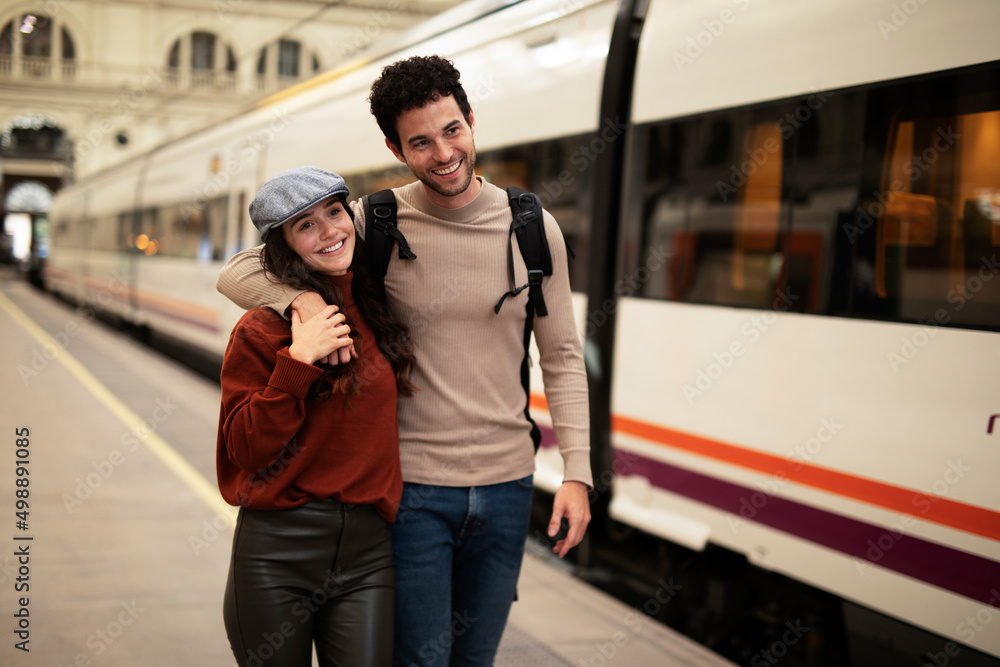 Beautiful couple at railway station waiting for the train. Young woman and man waiting to board a train.