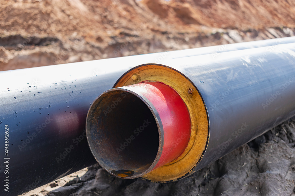 Insulated pipe. Large metal pipes with a plastic sheath laid in a trench. Modern pipeline for supplying hot water and heating to a residential area. Insulated pipe. Large metal pipes with a plastic sheath laid in a trench. Modern pipeline for supplying hot water and heating to a residential area.