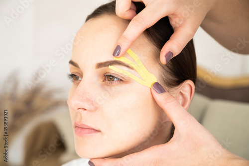 Close-up portrait of young woman with kinesio tapes on face. Anti-aging treatment against wrinkles