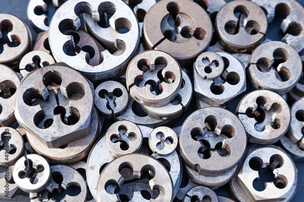Bolt threading dies. Many dies of different sizes, top view. Hand tool for making screw threads