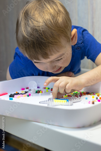 The child enthusiastically plays thermo mosaic. Boy 4 years