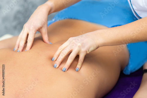 woman masseur doing back massage to client man on massage table, closeup © Ivan