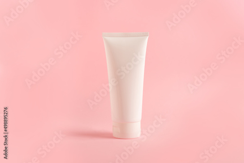 clean tube with body cream on pink background