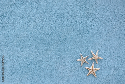 Flat lay three dry starfish on blue beach towel
