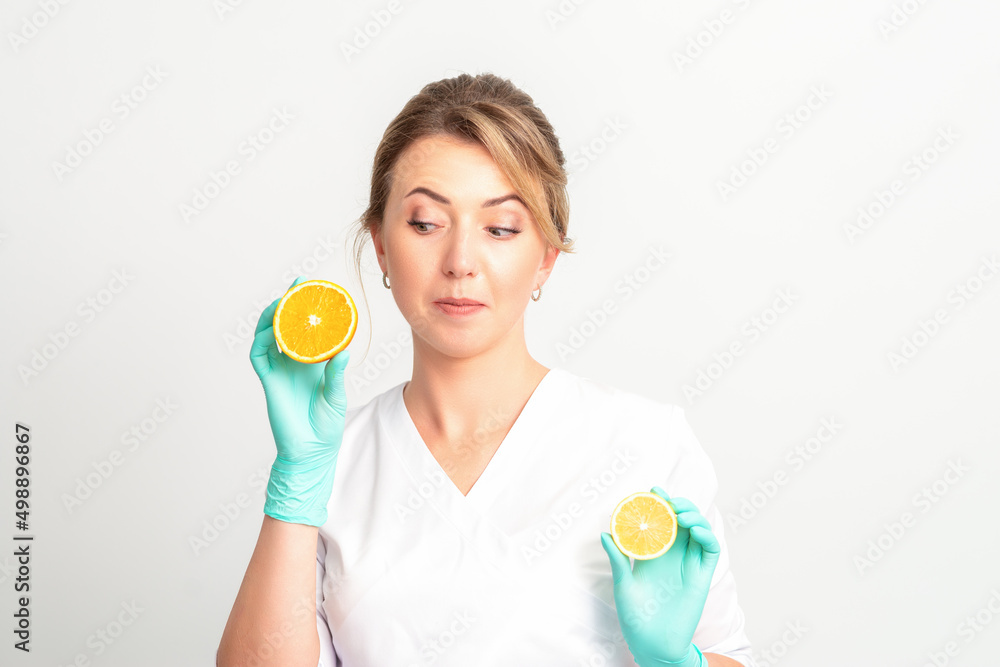Smiling female nutritionist holding a sliced orange, looking at camera over white background, healthy diet concept Smiling female nutritionist holding a sliced orange, looking at camera over white background, healthy diet concept
