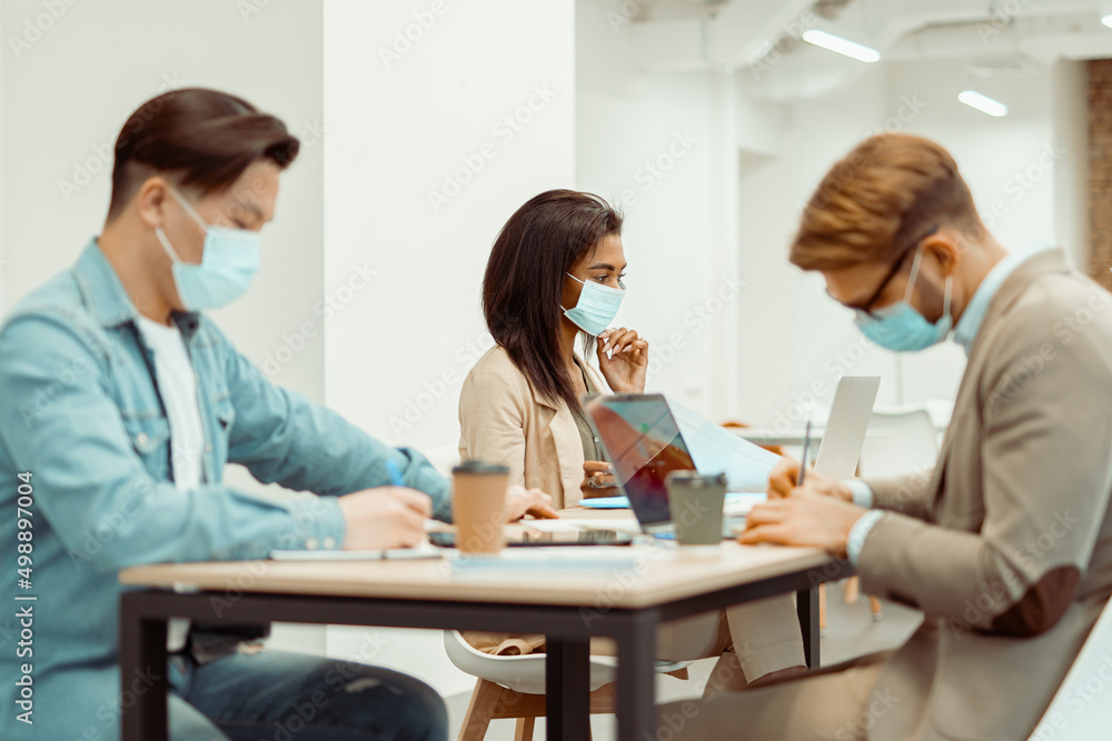 Two men and woman sitting at the table in the office
