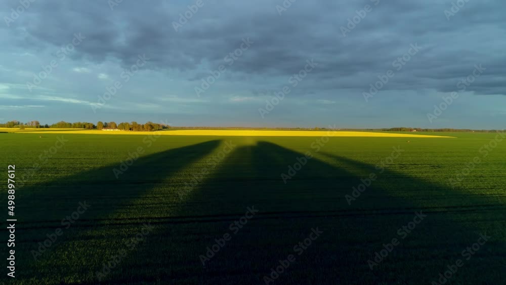 Ascending aerial shot of green agricultural field and yellow Canola Field in background during cloudy day Ascending aerial shot of green agricultural field and yellow Canola Field in background during cloudy day