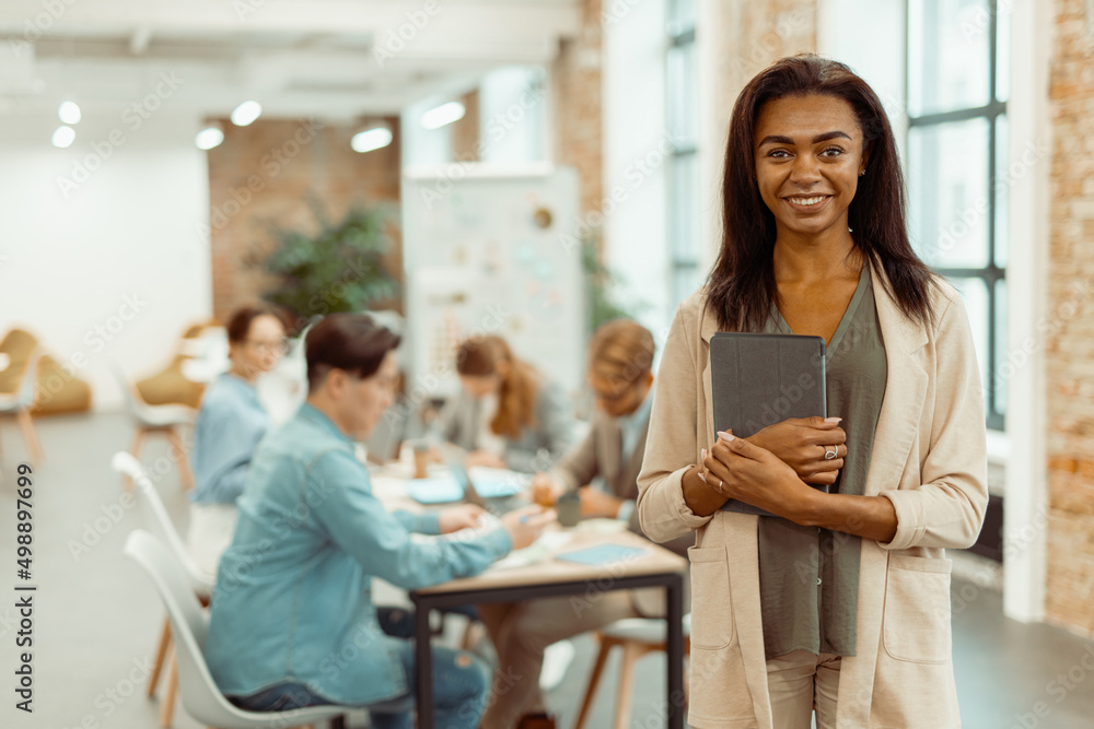 Smiling young woman standing with gadget in the office Smiling young woman standing with gadget in the office