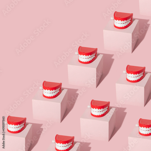 Fotografija Creative pattern with teeth toy on pastel pink cube on pastel pink background