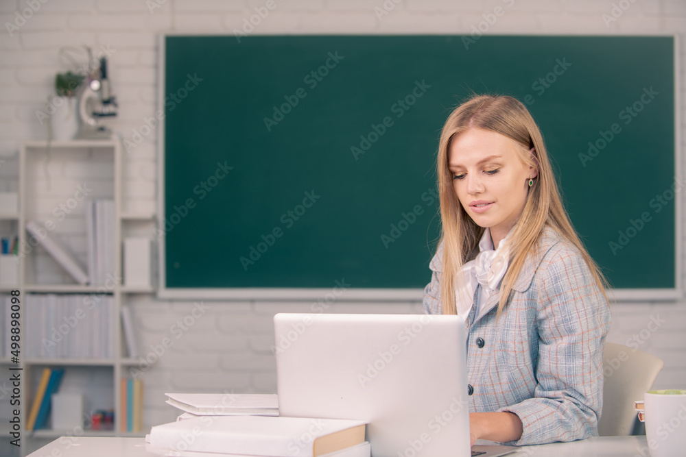Female student sitting at table and writing on notebook in classroom at high school or college. Female student sitting at table and writing on notebook in classroom at high school or college.
