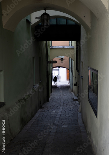 Silhouette of a man walking between houses along a narrow cobbled street