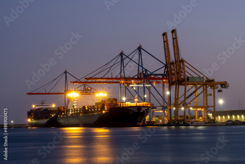 Huge cargo with a lot of containers parked in a harbor at night