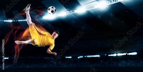 Active professional soccer, football player kick the ball in jump at dark night stadium with flashlights. Sport, competition, championship. Flyer, poster © master1305