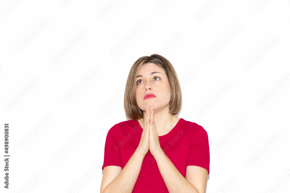 Horizontal image of a young Caucasian woman praying, looking up with open eyes, isolated on white background. Bob haircut and casual fuchsia t-shirt. Horizontal image of a young Caucasian woman praying, looking up with open eyes, isolated on white background. Bob haircut and casual fuchsia t-shirt.