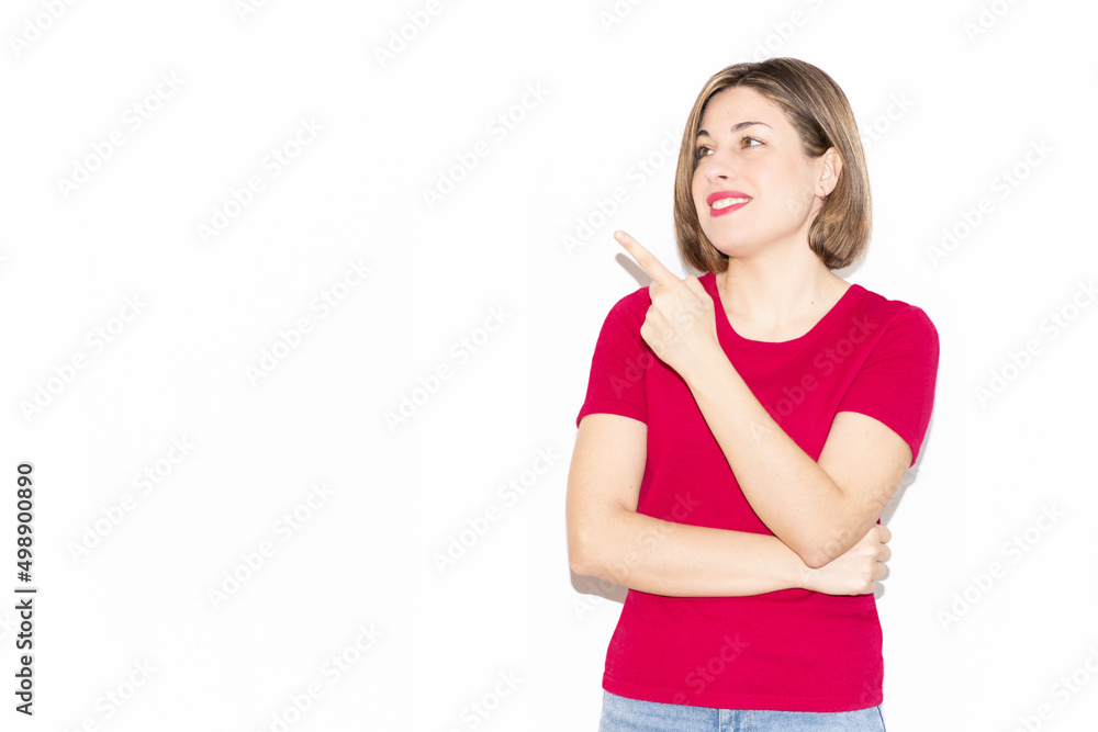 Horizontal photo of an adorable young woman dressed in casual pink clothing pointing to the empty blank space in the background, looking at what is pointed out. Horizontal photo of an adorable young woman dressed in casual pink clothing pointing to the empty blank space in the background, looking at what is pointed out.