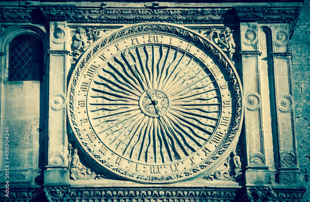Ancient astronomical clock in Sun shape on the facade of famous Chartres cathedral (France). Aged photo.