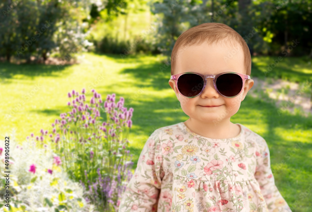 childhood and people concept - happy little baby girl in sunglasses over summer garden background childhood and people concept - happy little baby girl in sunglasses over summer garden background