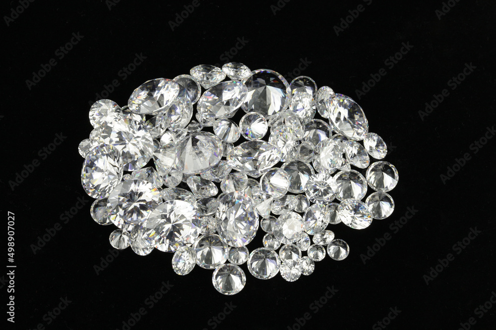Assorted loose polished diamonds on a black surface background. Assorted loose polished diamonds on a black surface background.