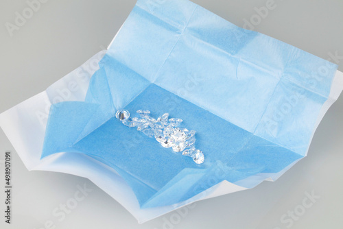 Parcel of loose diamonds with blue parcel paper on grey background