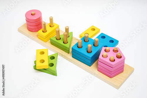 Wooden toy for baby, children isolated on white background. Shapes of different colors with holes.