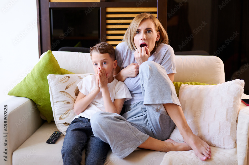 Family watching TV. Mother and son scared while watching a movie on the sofa Family watching TV. Mother and son scared while watching a movie on the sofa