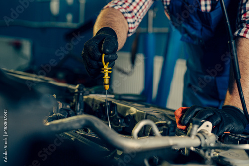 Car mechanic checking oil level in a mechanical workshop