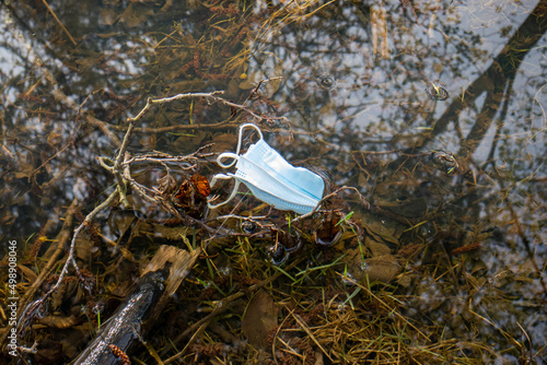 Covid face mask litter. Discarded face mask in a forest puddle. Day time, no people