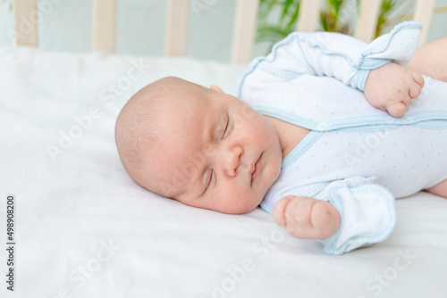 close-up of a newborn baby boy sleeping in a cot at home for seven days on a cotton bed, healthy baby sleep
