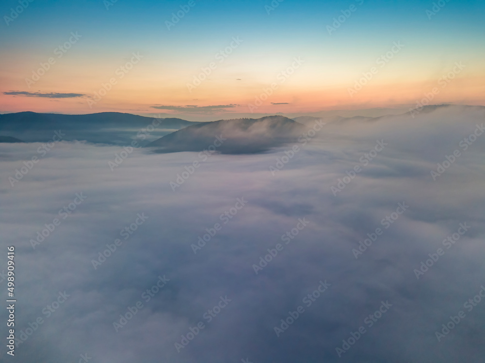 The rays of dawn over the fog in the Ukrainian Carpathians. Aerial drone view.