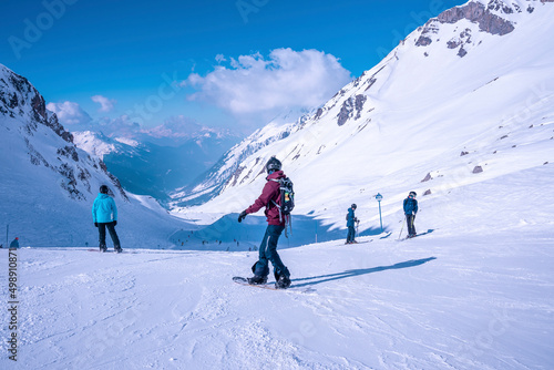 St. Anton am Arlberg. March 10, 2022. Snowboarders and skiers standing on slope against snow covered mountains at ski resort, People standing on snowy mountain slope on sunny day